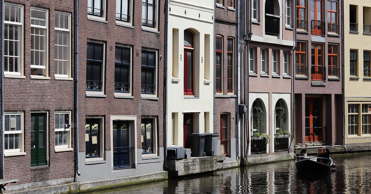 Benelux Production & Distribution Guide: Netherlands, Belgium, and Luxembourg 4 Row of traditional Amsterdam canal houses reflected in the water, representing the Dutch film production hub of the Netherlands.