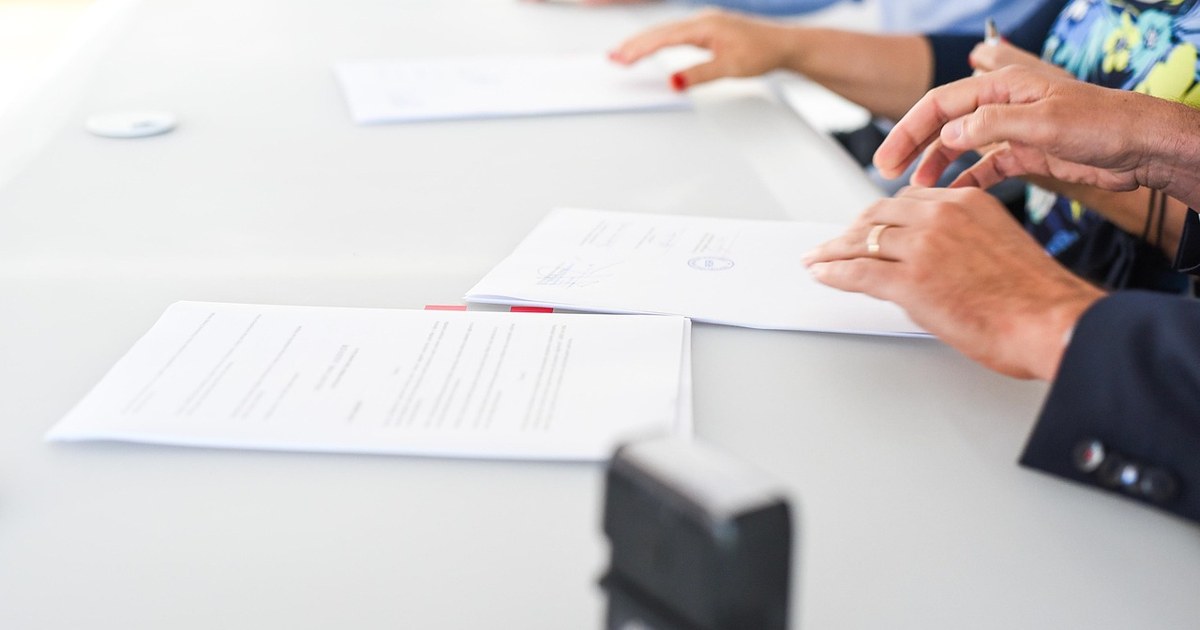 Two professionals finalizing and stamping a signed completion financing agreement, representing a film completion bond or gap financing contract.