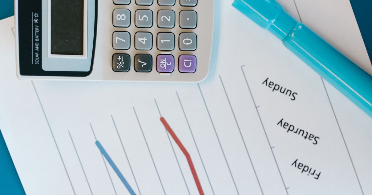 Calculator resting on a printed weekly budget chart, representing production cost report tracking