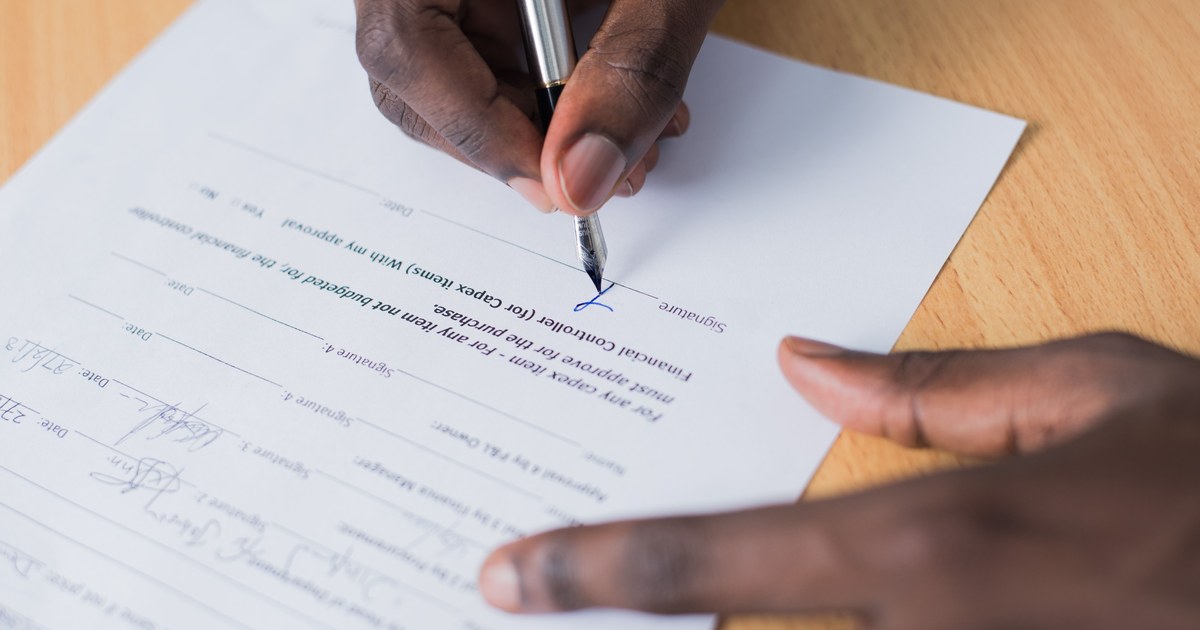 Hand signing a formal document, representing a co-production treaty agreement
